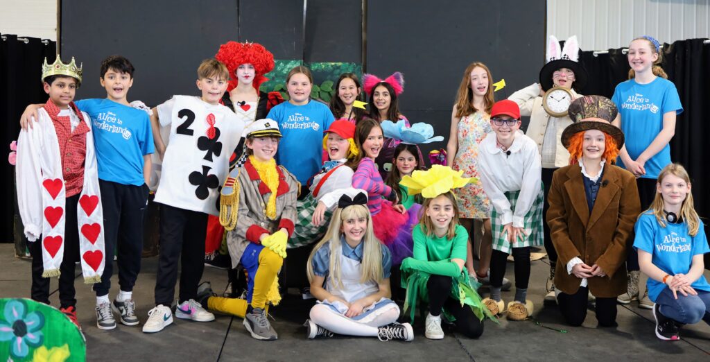 The full cast of "Alice in Wonderland" pose on stage after the show, in costume.